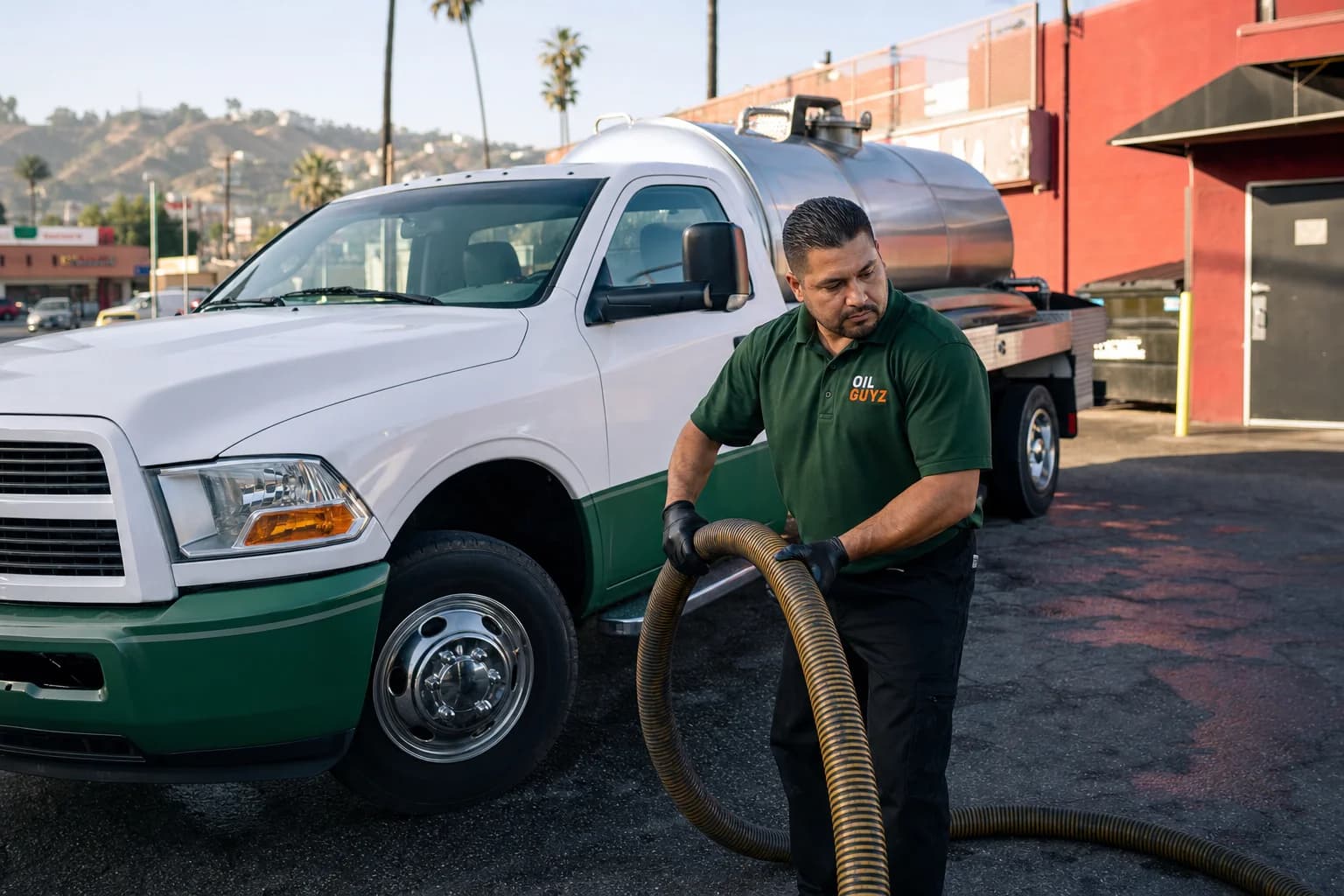 Free used cooking oil pickup at a Compton restaurant — unbranded white pump truck with hunter-green Oil Guyz technician