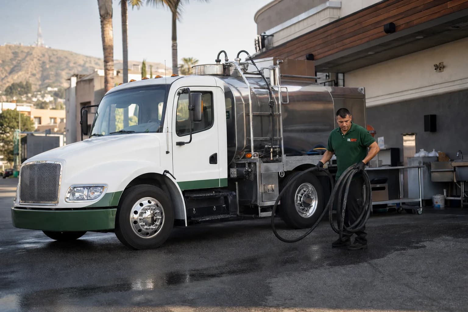 Free used cooking oil pickup at a Duarte restaurant — unbranded white pump truck with hunter-green Oil Guyz technician