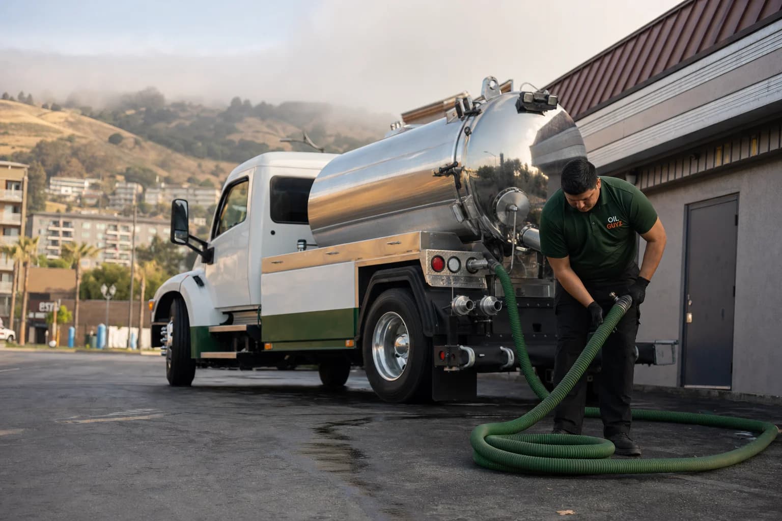 Free used cooking oil pickup at a Fremont restaurant — unbranded white pump truck with hunter-green Oil Guyz technician