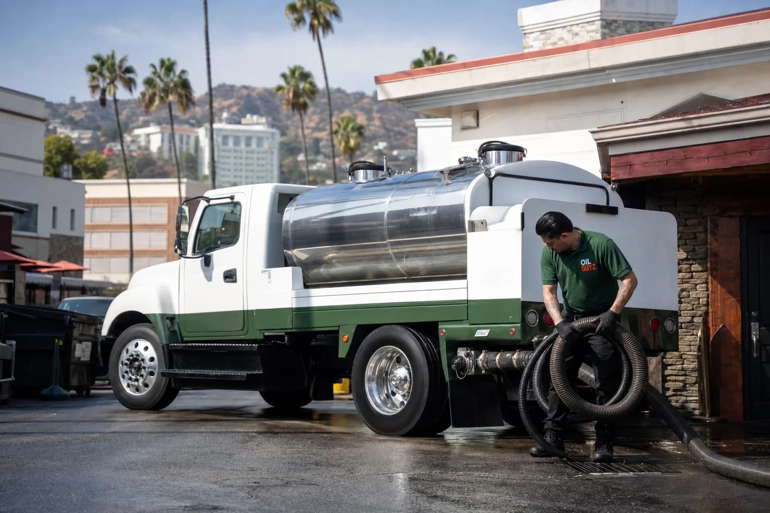 Free used cooking oil pickup at a Irwindale restaurant — unbranded white pump truck with hunter-green Oil Guyz technician