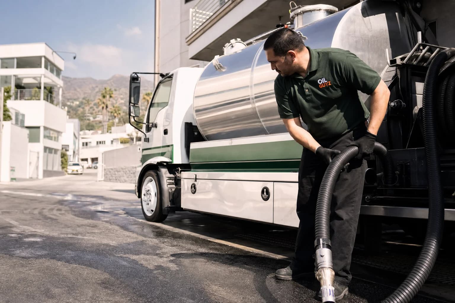 Free used cooking oil pickup at a La Cañada Flintridge restaurant — unbranded white pump truck with hunter-green Oil Guyz technician