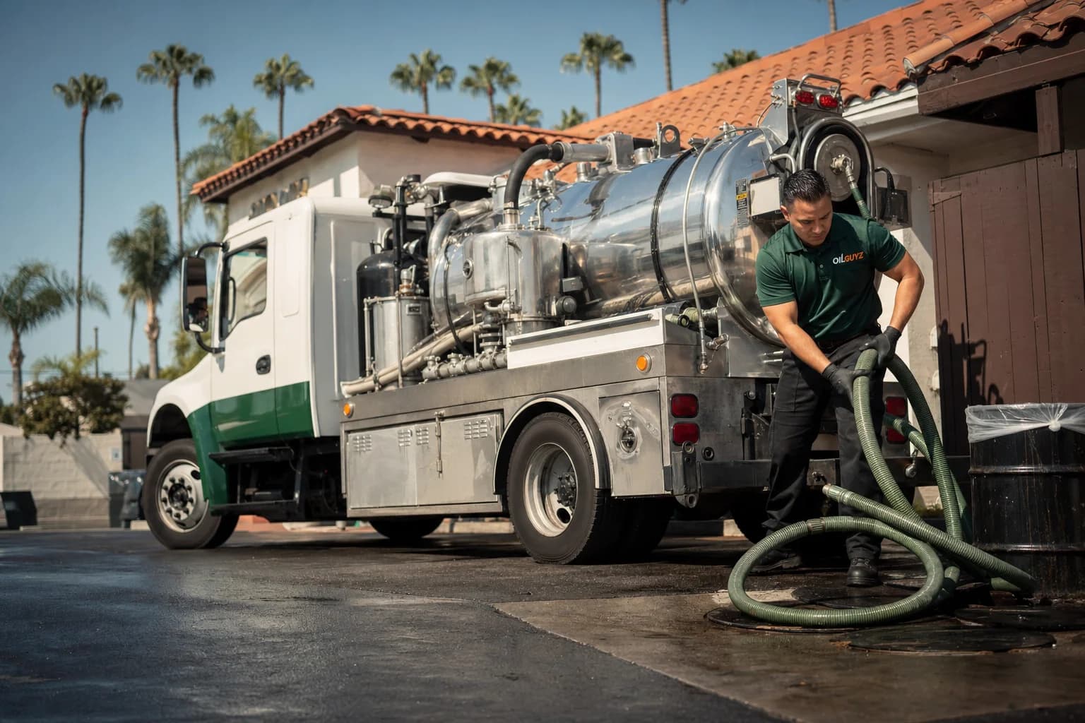 Free used cooking oil pickup at a Los Alamitos restaurant — unbranded white pump truck with hunter-green Oil Guyz technician
