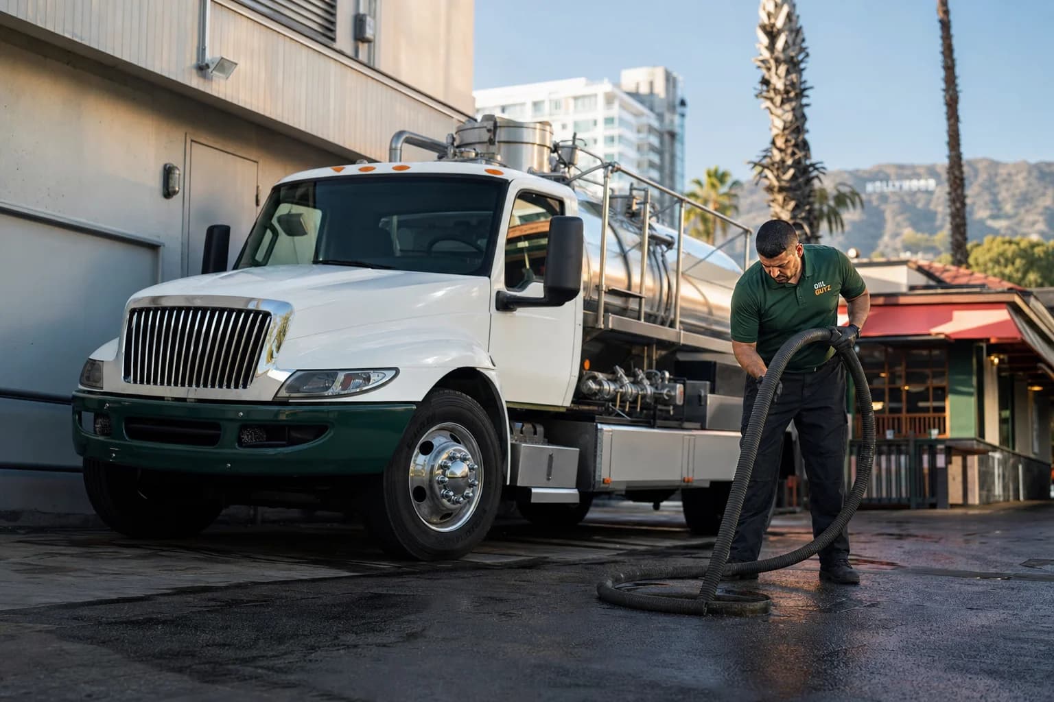 Free used cooking oil pickup at a Norwalk restaurant — unbranded white pump truck with hunter-green Oil Guyz technician