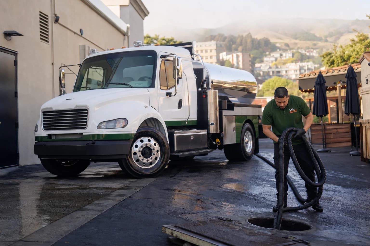 Free used cooking oil pickup at a Pleasanton restaurant — unbranded white pump truck with hunter-green Oil Guyz technician
