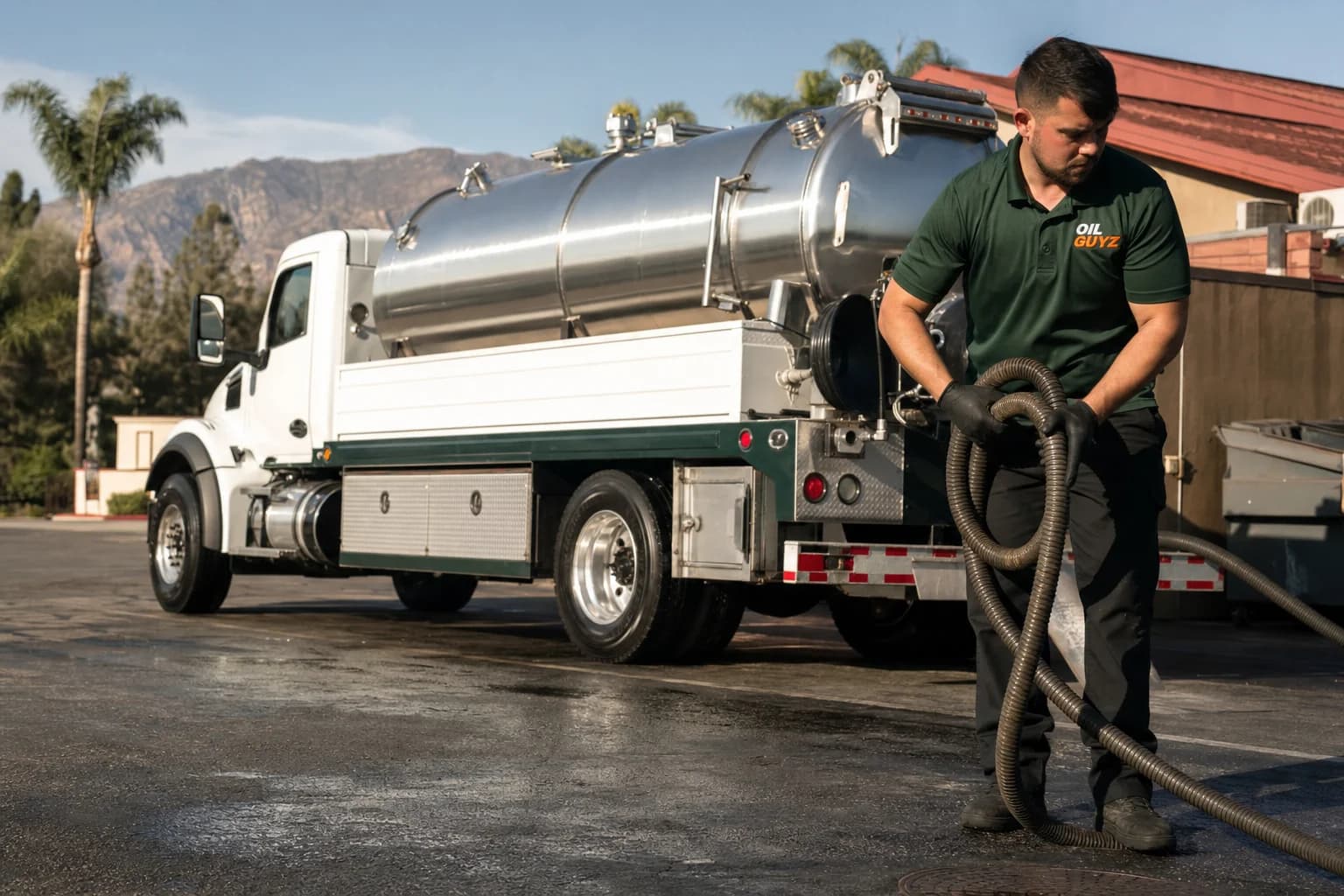 Free used cooking oil pickup at a Redlands restaurant — unbranded white pump truck with hunter-green Oil Guyz technician