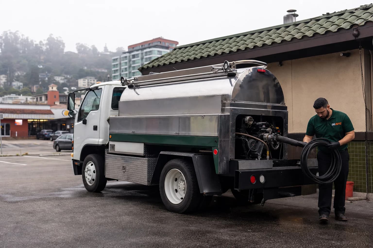 Free used cooking oil pickup at a Redwood City restaurant — unbranded white pump truck with hunter-green Oil Guyz technician