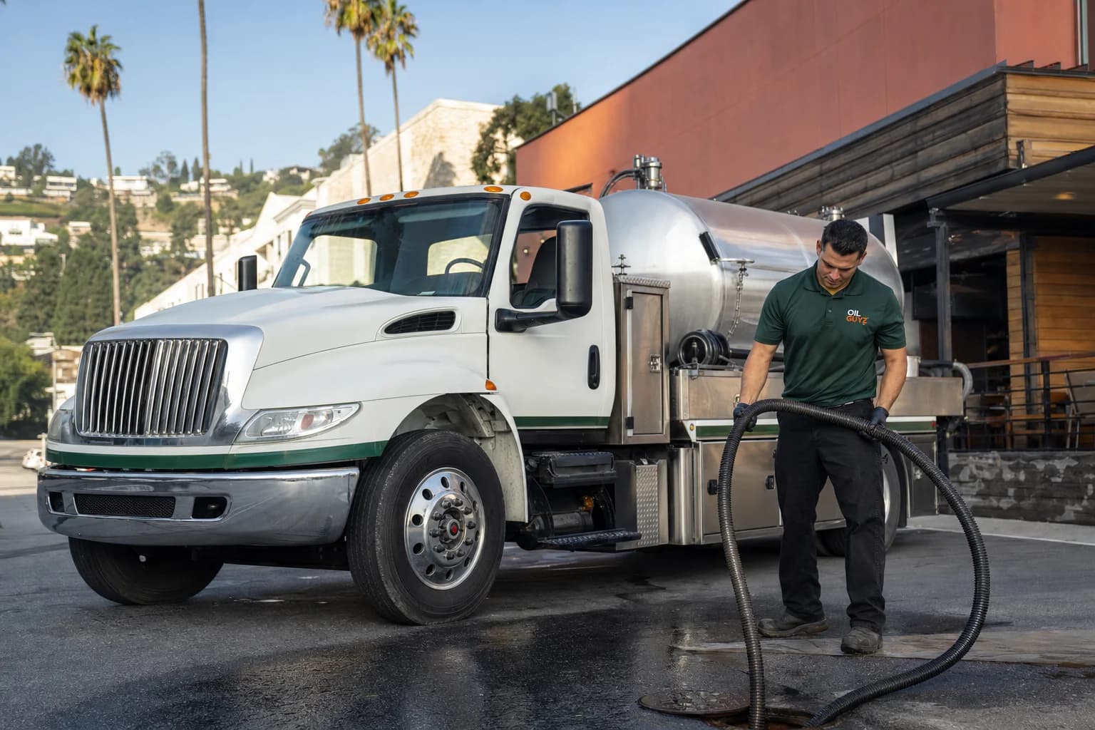 Free used cooking oil pickup at a Rolling Hills Estates restaurant — unbranded white pump truck with hunter-green Oil Guyz technician