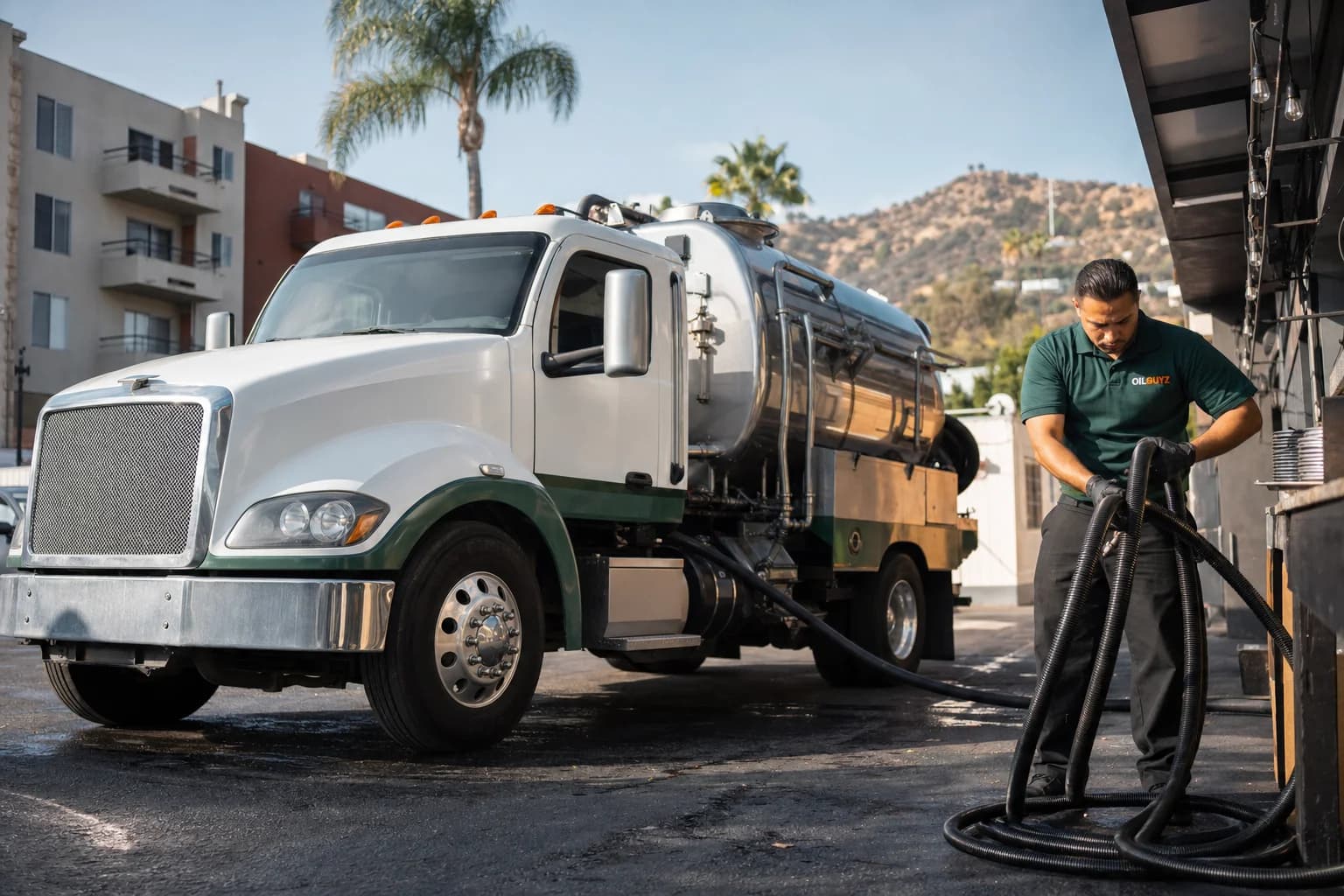 Free used cooking oil pickup at a San Fernando restaurant — unbranded white pump truck with hunter-green Oil Guyz technician