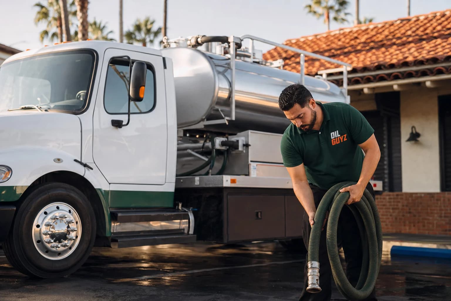 Free used cooking oil pickup at a Seal Beach restaurant — unbranded white pump truck with hunter-green Oil Guyz technician