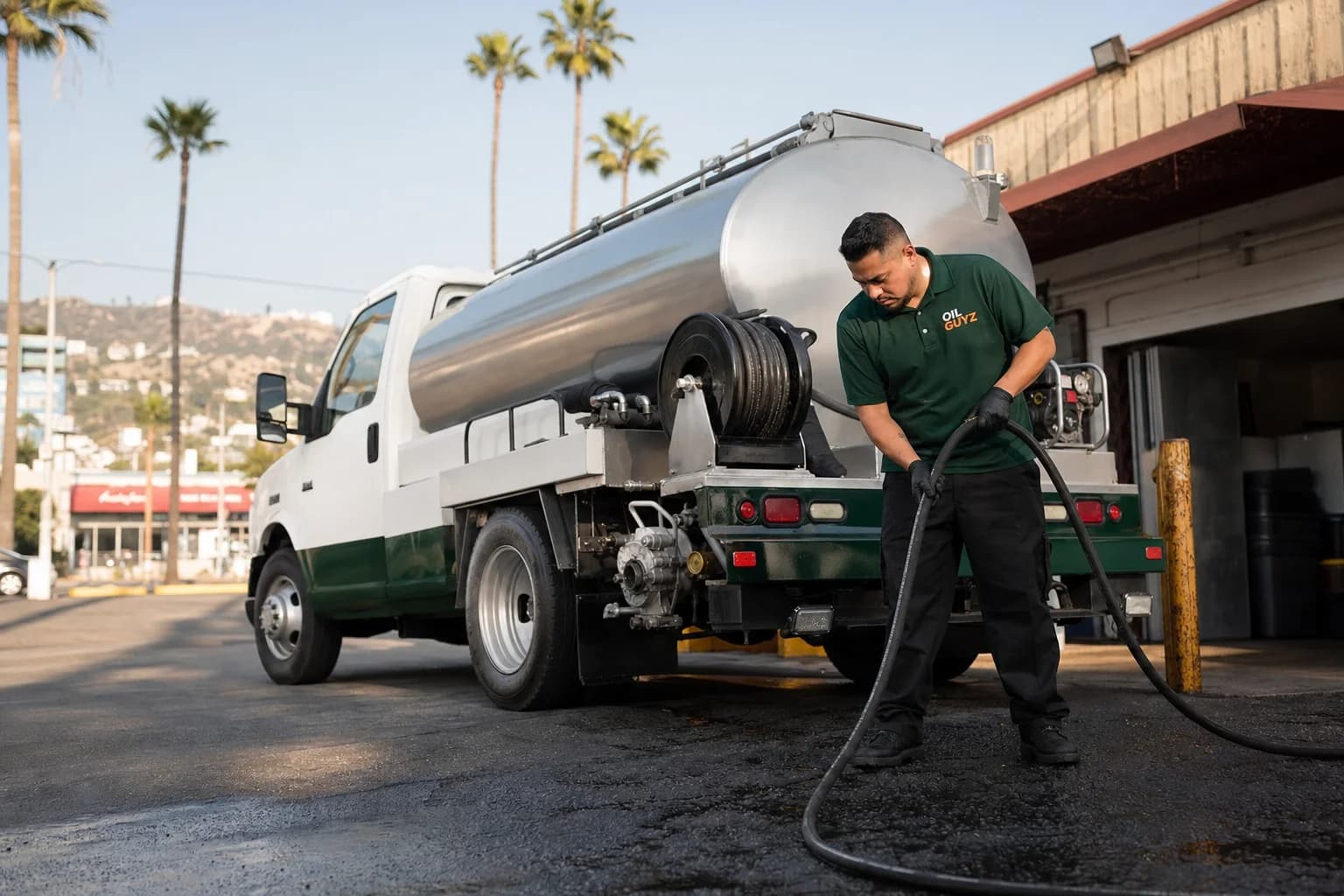 Free used cooking oil pickup at a South Gate restaurant — unbranded white pump truck with hunter-green Oil Guyz technician
