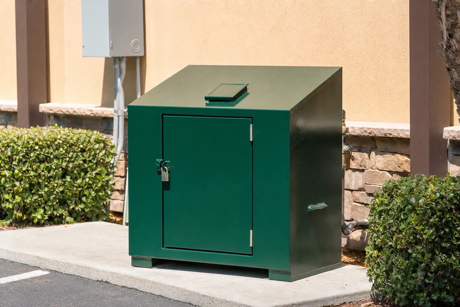 A locked used cooking oil collection bin behind a restaurant with a route driver preparing to empty it on schedule
