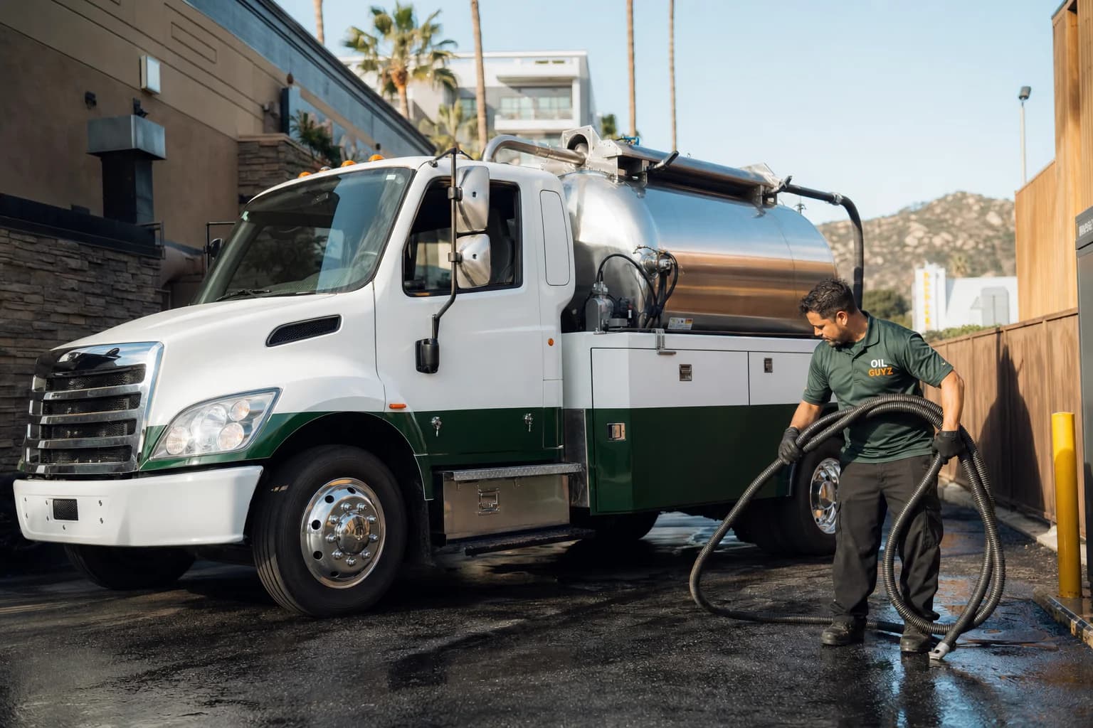 Free used cooking oil pickup at a Agoura Hills restaurant — unbranded white pump truck with hunter-green Oil Guyz technician