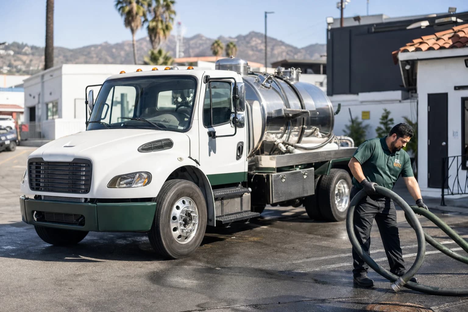 Free used cooking oil pickup at a Baldwin Park restaurant — unbranded white pump truck with hunter-green Oil Guyz technician