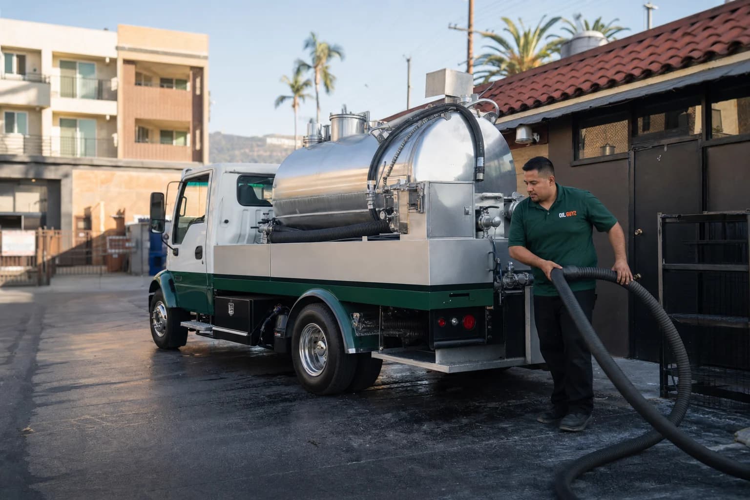 Free used cooking oil pickup at a Bell Gardens restaurant — unbranded white pump truck with hunter-green Oil Guyz technician