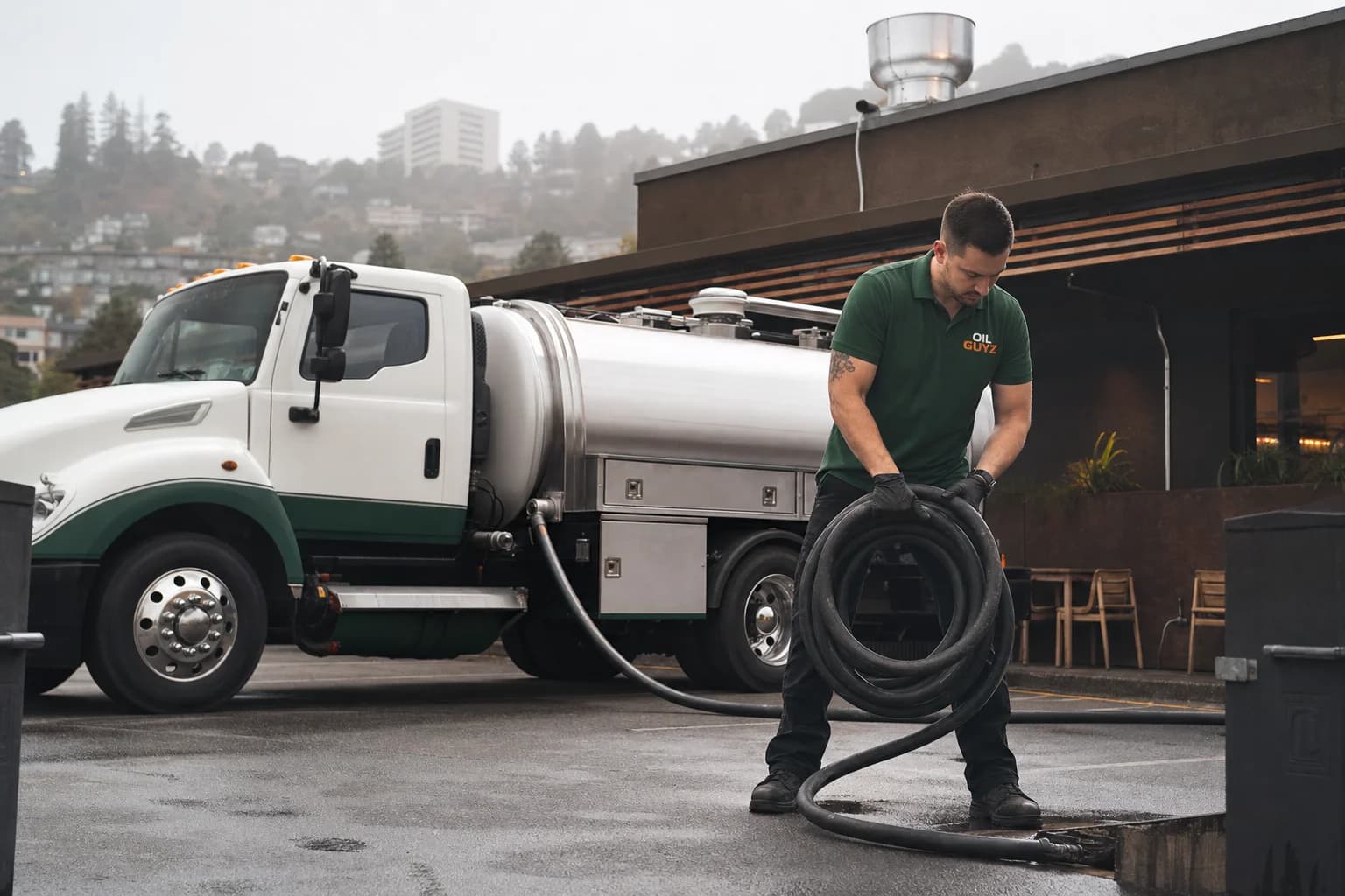 Free used cooking oil pickup at a Burlingame restaurant — unbranded white pump truck with hunter-green Oil Guyz technician