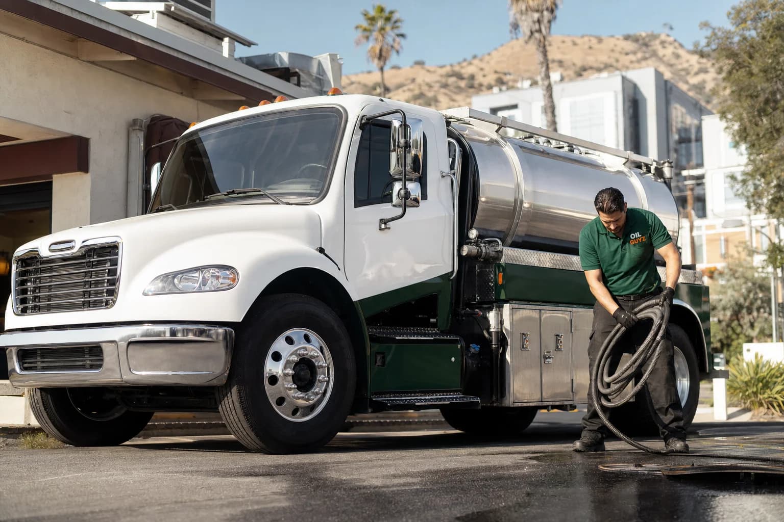 Free used cooking oil pickup at a Carson restaurant — unbranded white pump truck with hunter-green Oil Guyz technician
