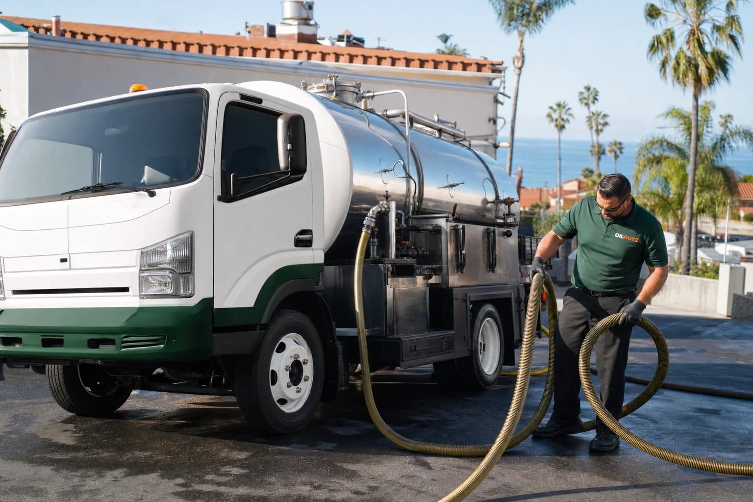 Free used cooking oil pickup at a Chula Vista restaurant — unbranded white pump truck with hunter-green Oil Guyz technician