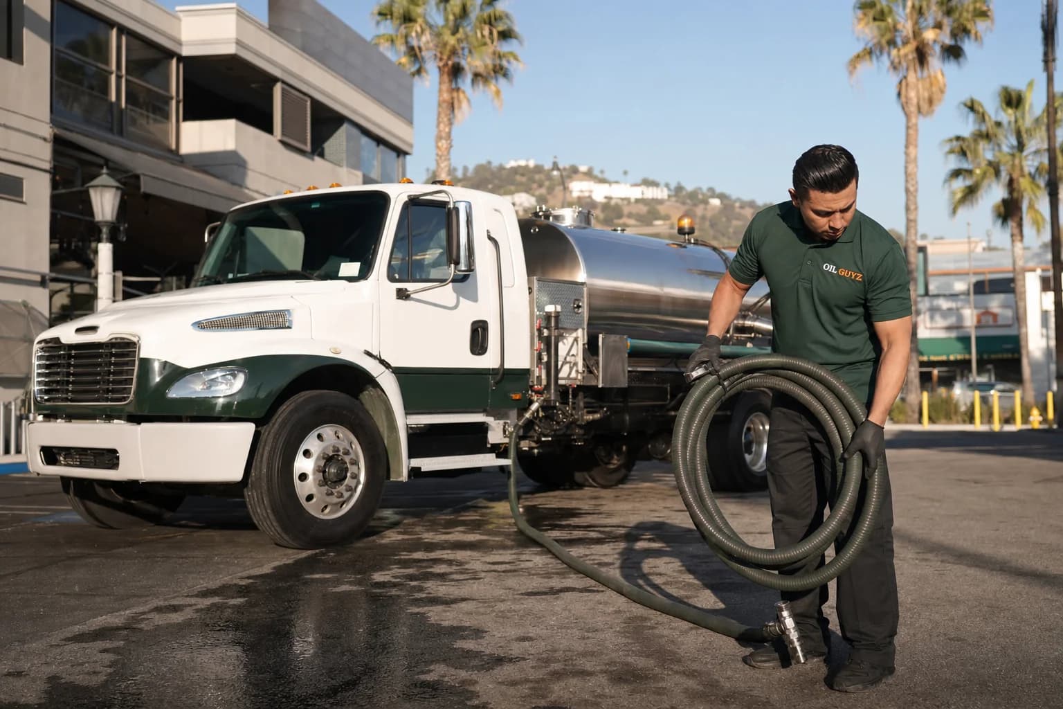 Free used cooking oil pickup at a Claremont restaurant — unbranded white pump truck with hunter-green Oil Guyz technician