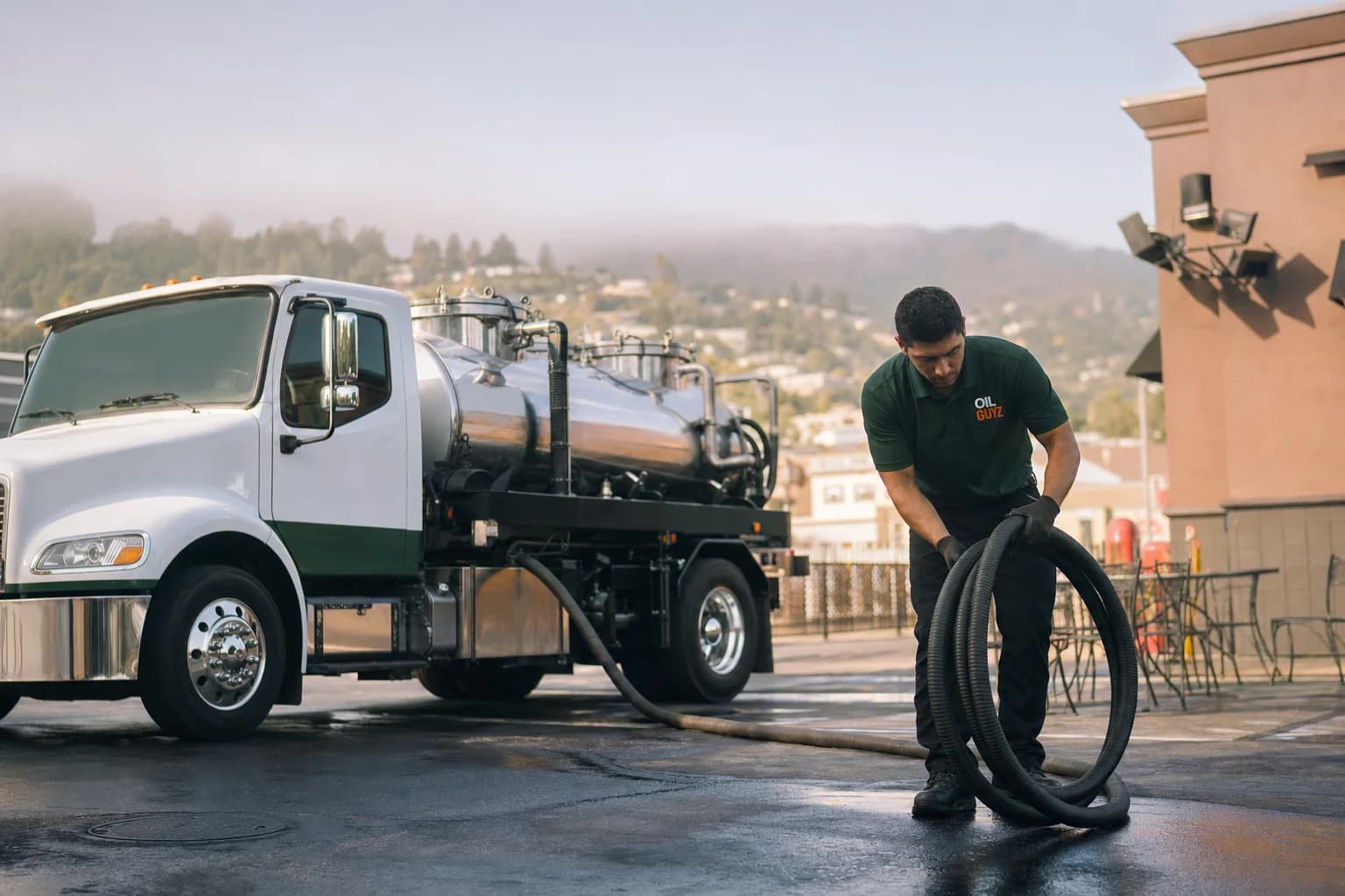 Free used cooking oil pickup at a Concord restaurant — unbranded white pump truck with hunter-green Oil Guyz technician