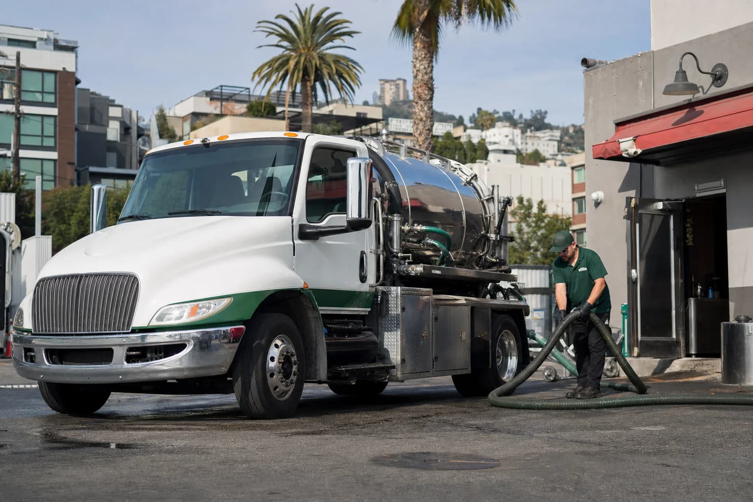Free used cooking oil pickup at a Culver City restaurant — unbranded white pump truck with hunter-green Oil Guyz technician