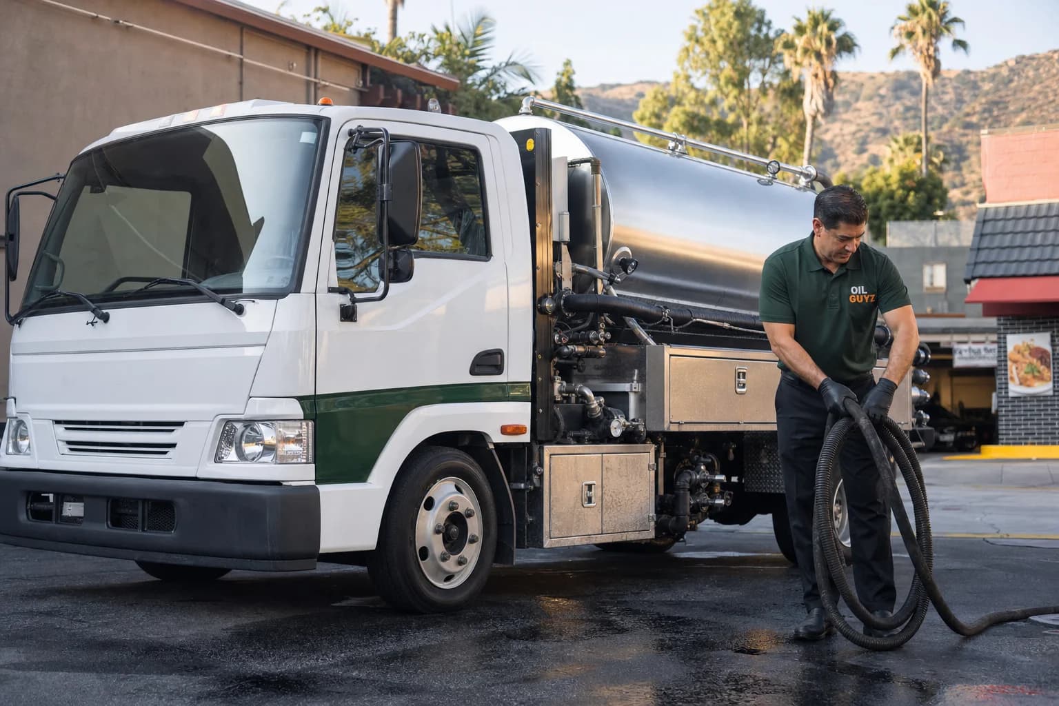 Free used cooking oil pickup at a Hawaiian Gardens restaurant — unbranded white pump truck with hunter-green Oil Guyz technician