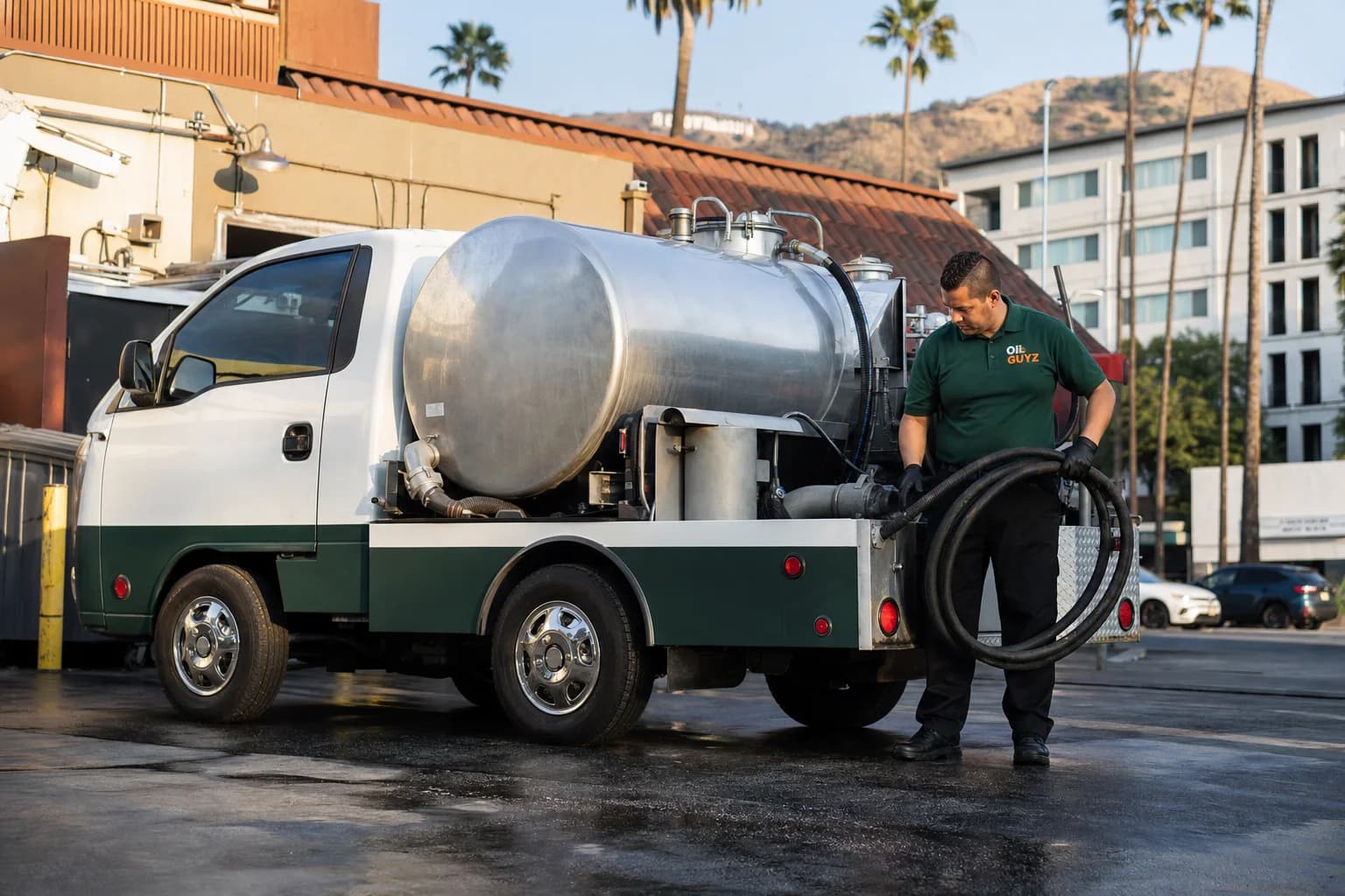 Free used cooking oil pickup at a Lawndale restaurant — unbranded white pump truck with hunter-green Oil Guyz technician