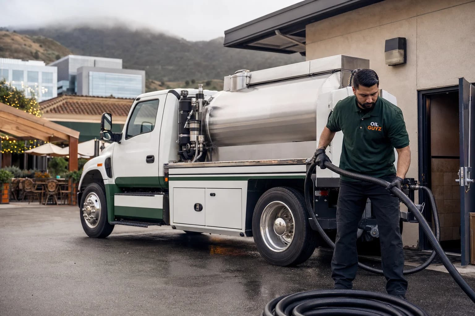 Free used cooking oil pickup at a Mountain View restaurant — unbranded white pump truck with hunter-green Oil Guyz technician