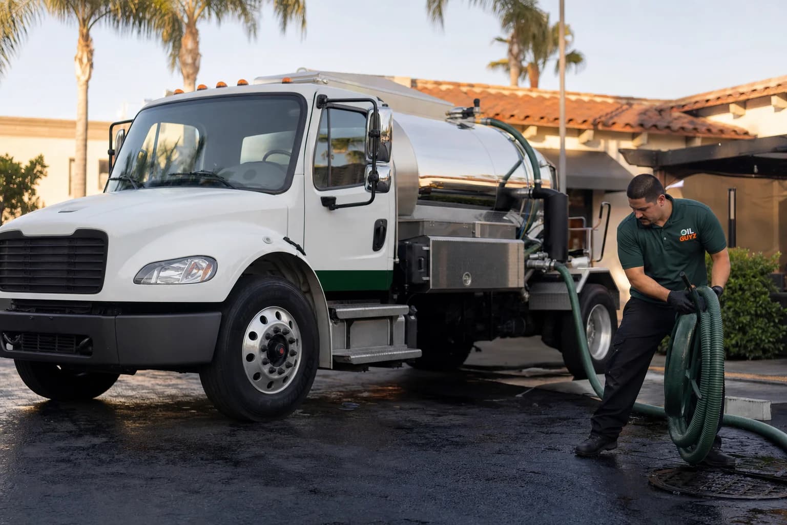 Free used cooking oil pickup at a Newport Beach restaurant — unbranded white pump truck with hunter-green Oil Guyz technician