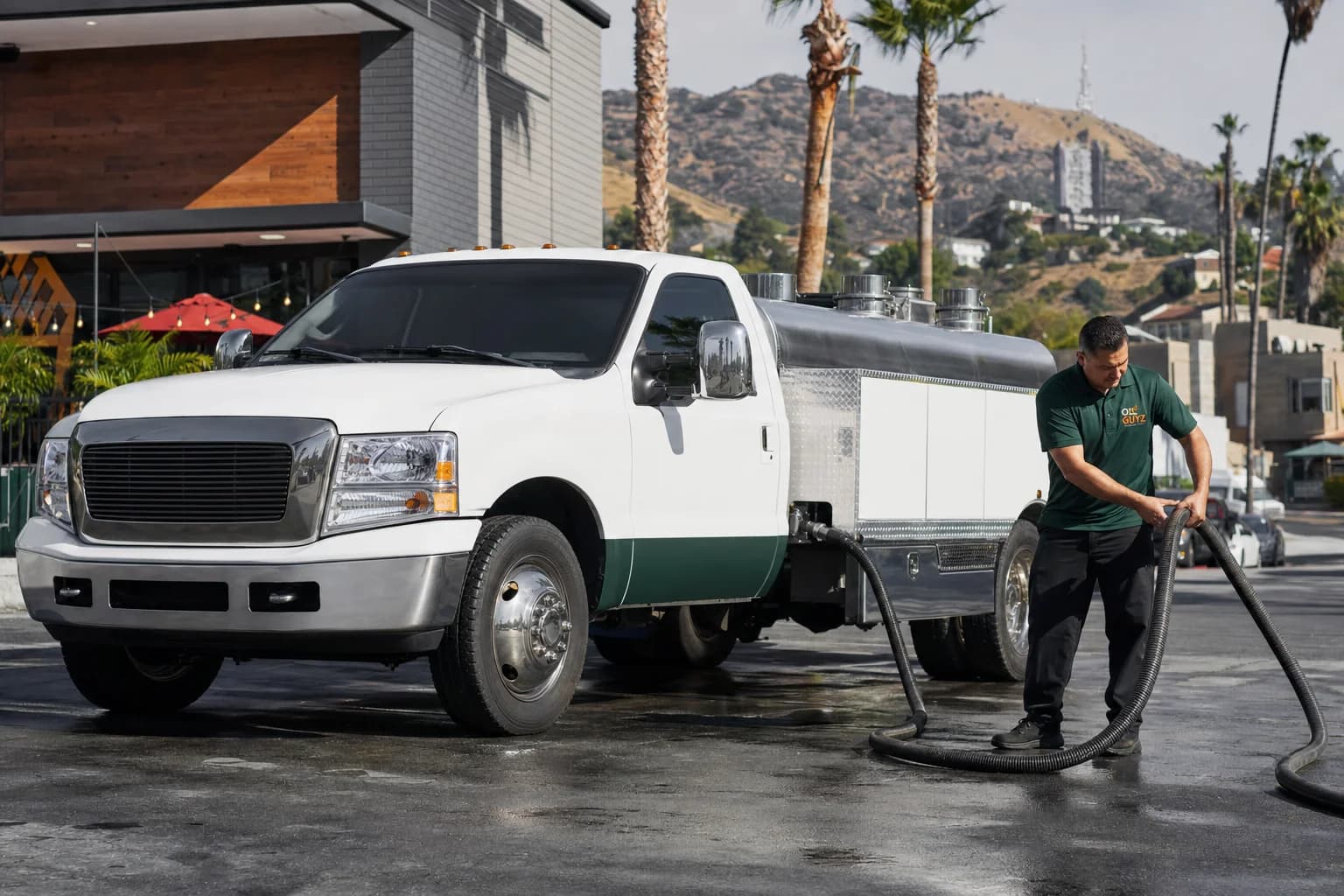 Free used cooking oil pickup at a Rolling Hills restaurant — unbranded white pump truck with hunter-green Oil Guyz technician