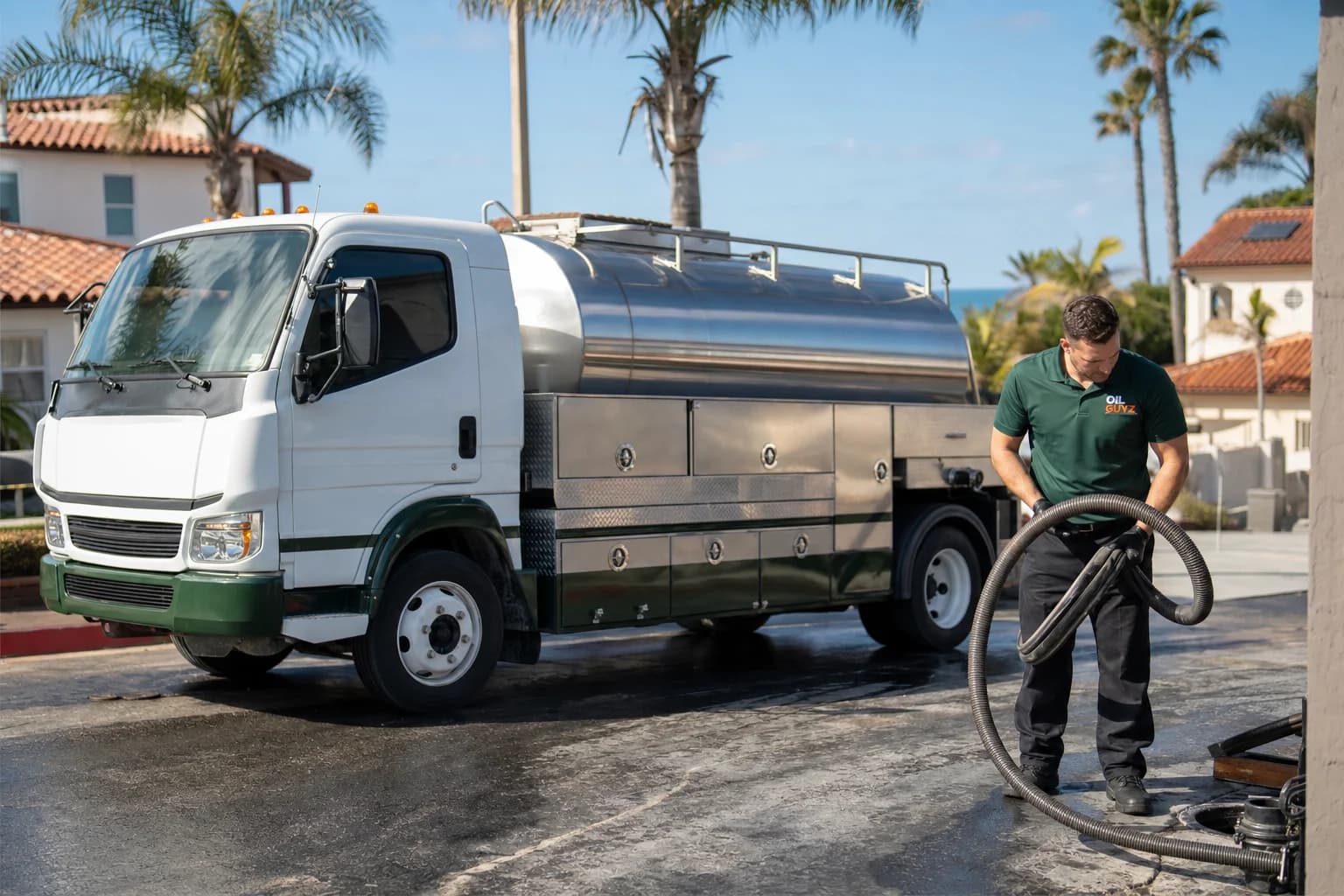 Free used cooking oil pickup at a Solana Beach restaurant — unbranded white pump truck with hunter-green Oil Guyz technician