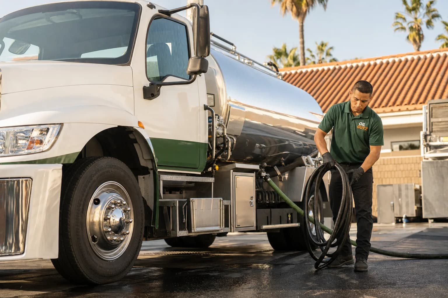 Free used cooking oil pickup at a Stanton restaurant — unbranded white pump truck with hunter-green Oil Guyz technician