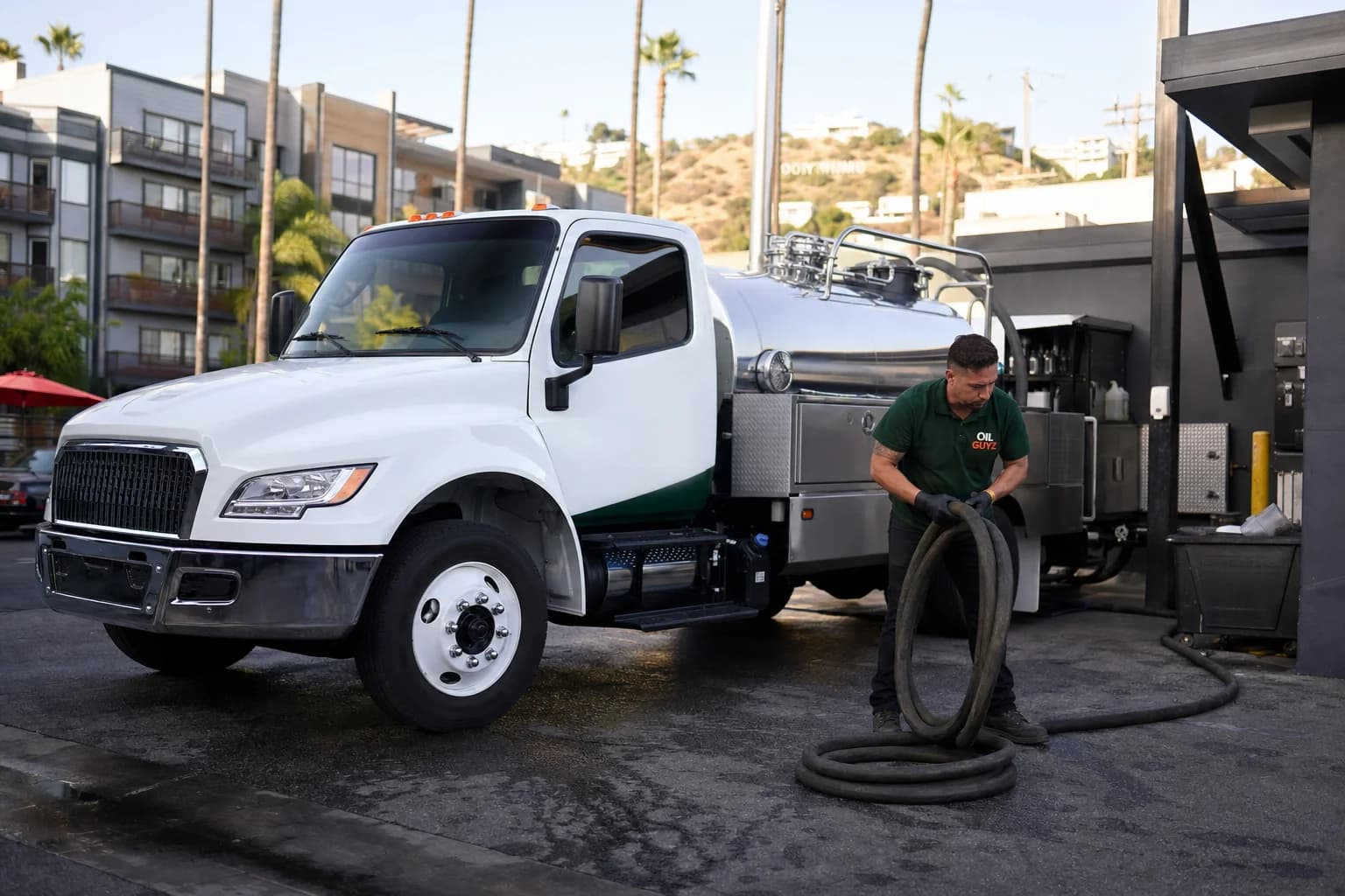 Free used cooking oil pickup at a Vernon restaurant — unbranded white pump truck with hunter-green Oil Guyz technician