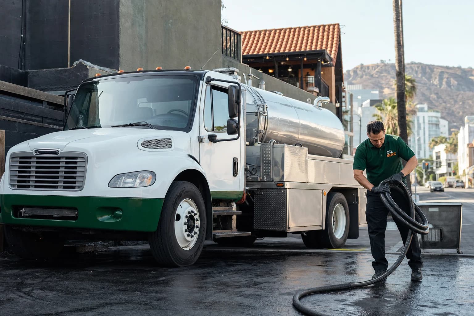 Free used cooking oil pickup at a West Hollywood restaurant — unbranded white pump truck with hunter-green Oil Guyz technician